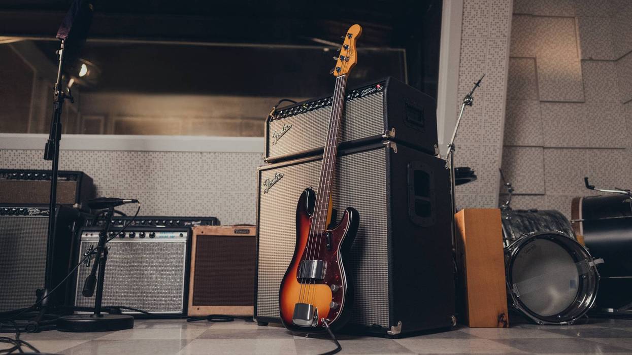 A bass guitar leaning against amplifier stacks in a music studio setting.