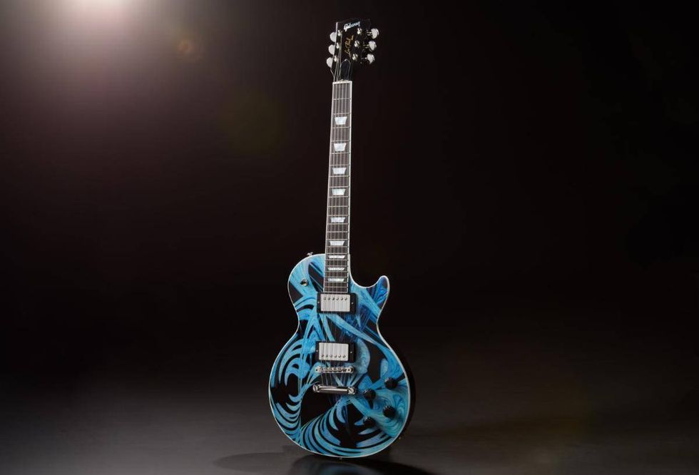 A blue electric guitar with intricate swirling patterns, set against a dark background.