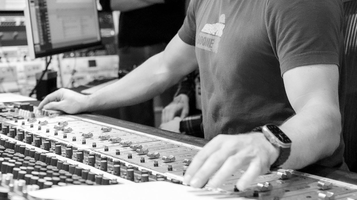 A close-up of a person's hands adjusting knobs on a sound mixing console.