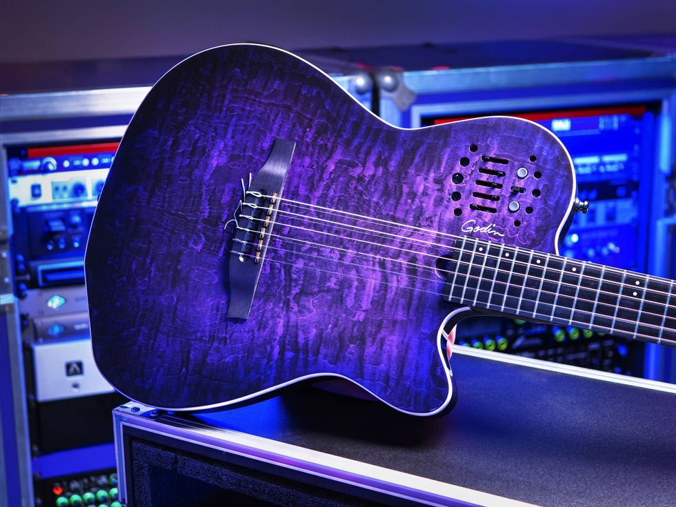 A close-up of a purple-accented guitar with electronic features against a studio backdrop.