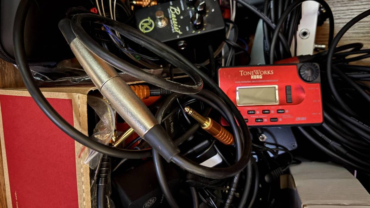 A cluttered collection of audio equipment, cables, and effects pedals.