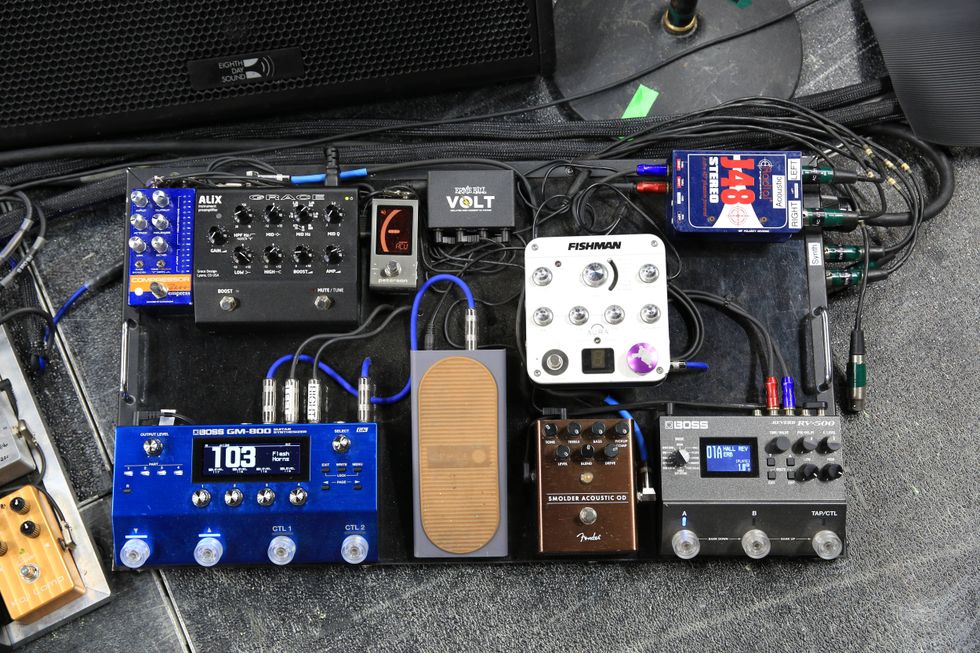 A collection of guitar effects pedals arranged on a board with various cables and controls.