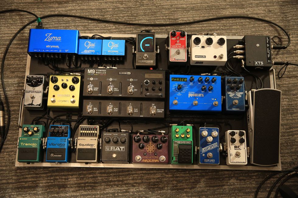 A collection of guitar pedals arranged on a metal board, featuring various brands and models.