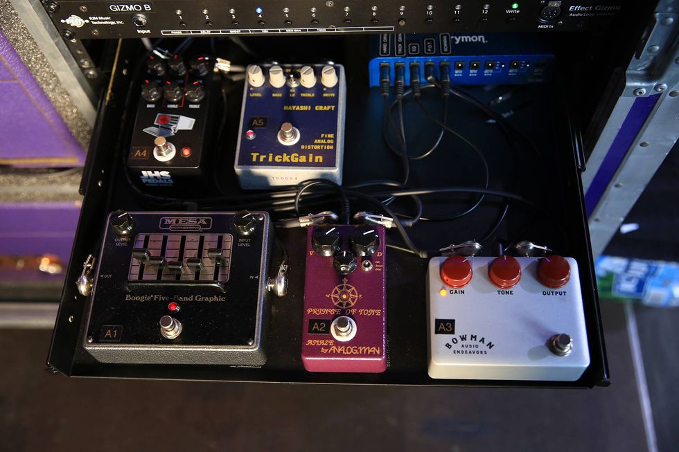A collection of guitar pedals in a rack, featuring various effects and controls.