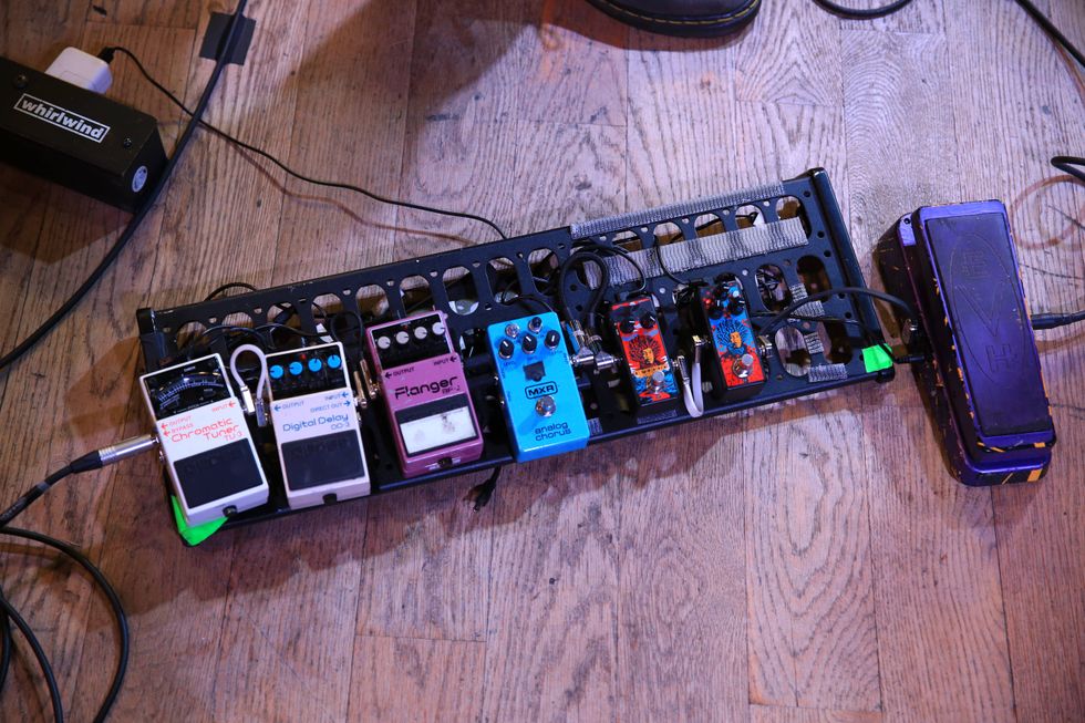 A collection of guitar pedals on a board, including tuners, delays, and a wah pedal.