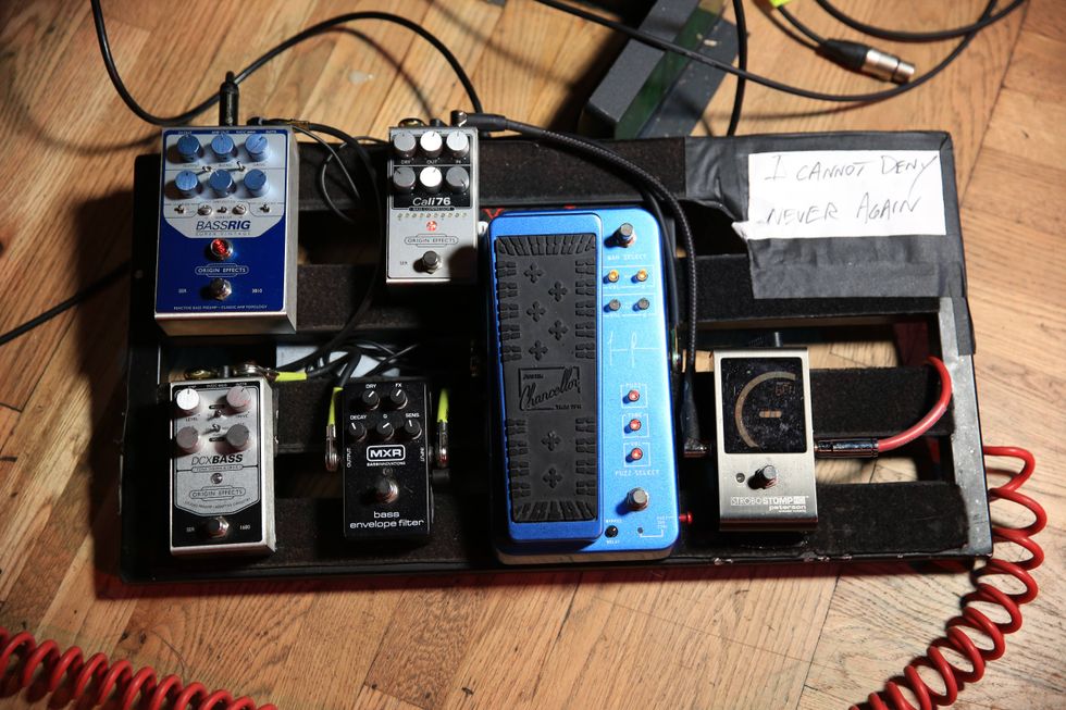 A collection of guitar pedals on a board with a note saying "I cannot deny never again."