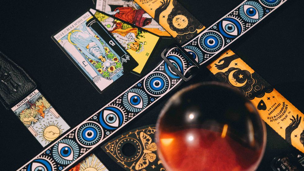 A collection of tarot cards and a crystal ball on a dark surface, surrounded by mystical designs.