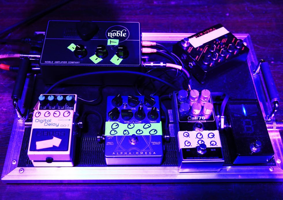 A colorful collection of guitar pedals on a pedalboard under purple lighting.