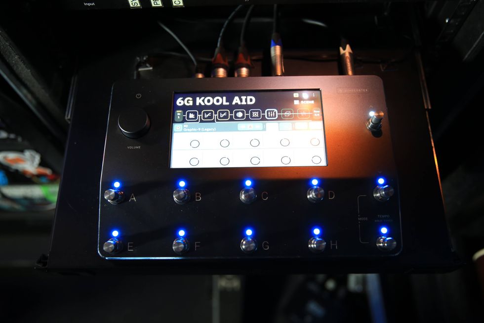 A digital pedalboard with labeled buttons and a display screen featuring musical controls.