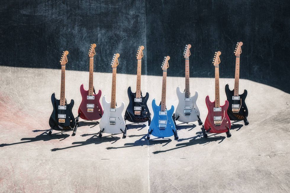A lineup of ten electric guitars in various colors displayed on a textured surface.