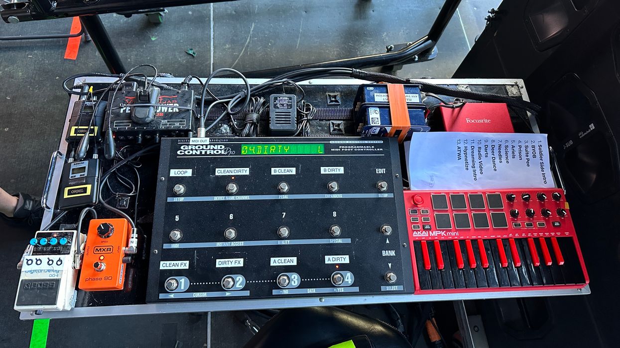 A MIDI controller setup with pedals, switches, and a music setlist on a table.