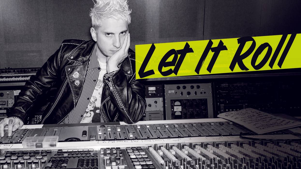 A musician poses at a mixing console, wearing a leather jacket with