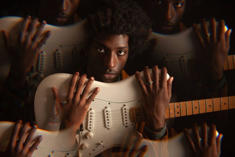 A musician poses with a guitar, surrounded by multiple reflections.