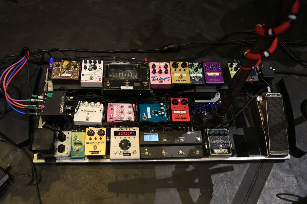 A musician's pedalboard displaying various effects pedals and a volume pedal.