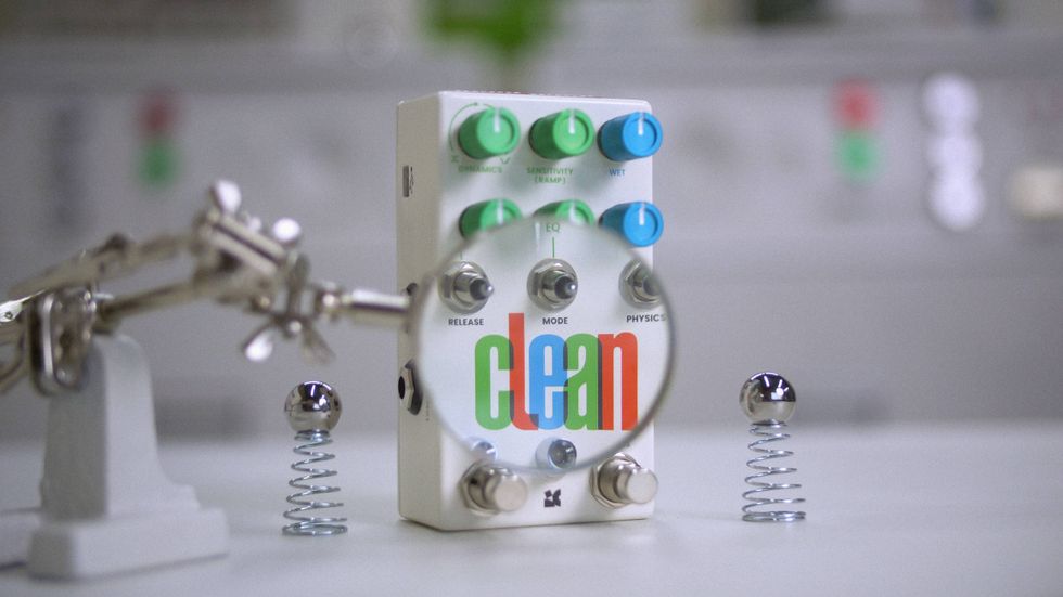 A pedal labeled "clean" with colorful knobs, under a magnifying glass, near springs.