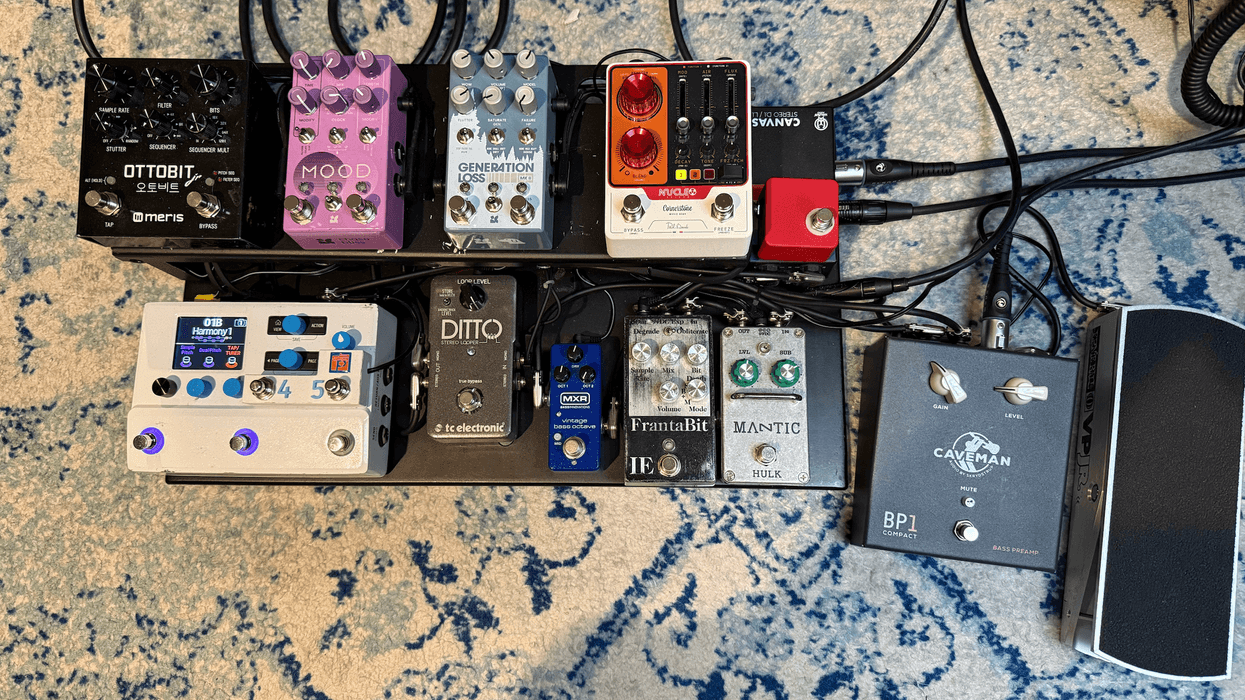 A pedalboard featuring various guitar effects pedals and intricate cable connections.