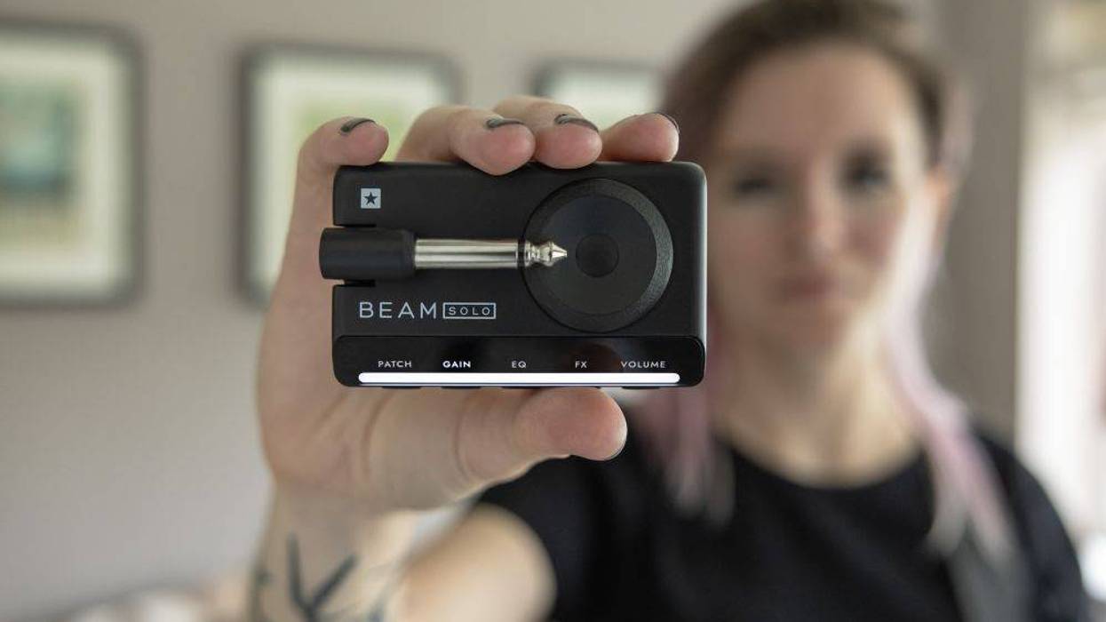 A person holds a black audio device labeled