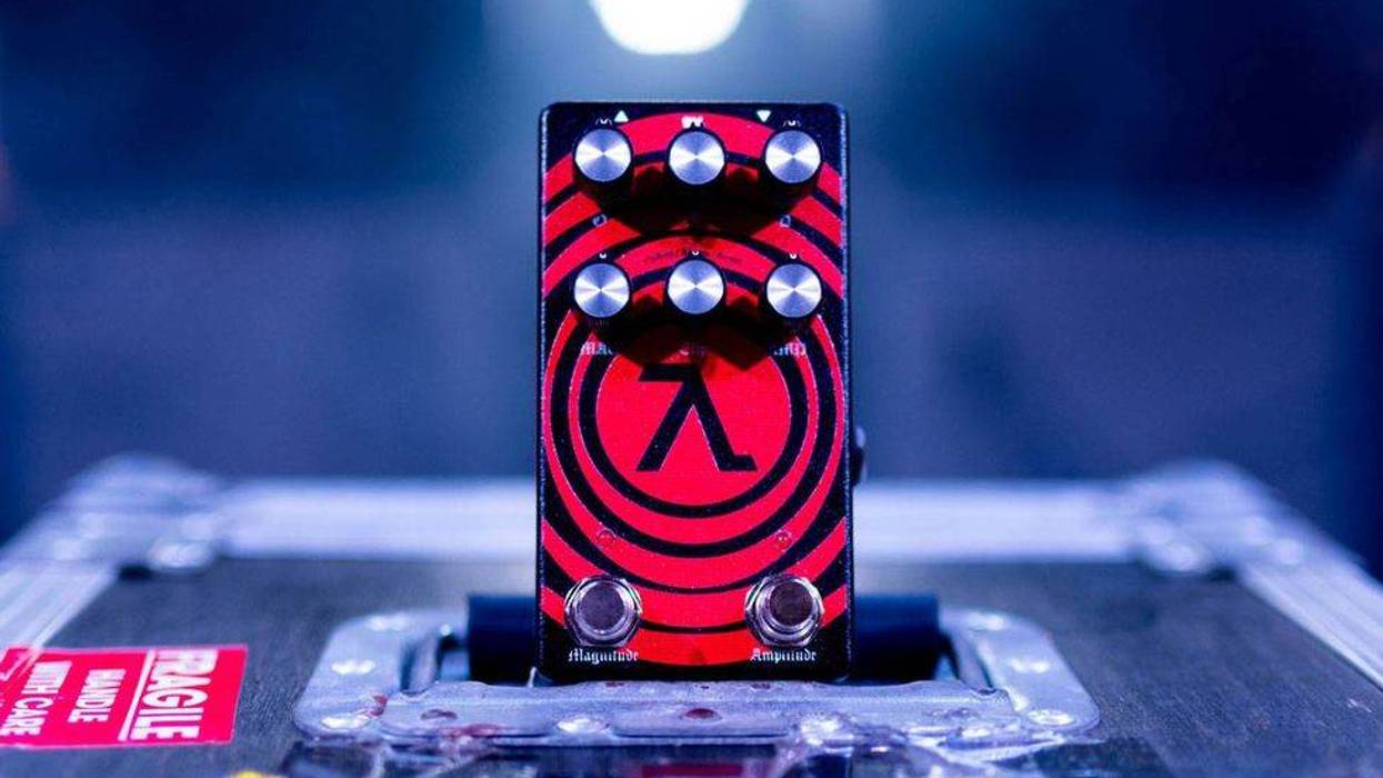 A red and black guitar effects pedal sits on a case, featuring knobs and a prominent logo.