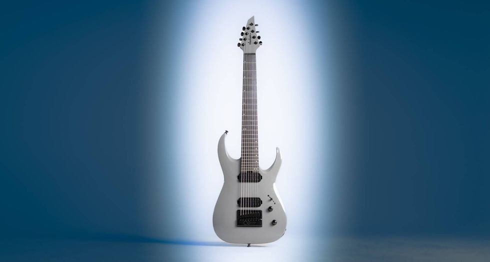 A sleek white electric guitar stands against a softly lit blue background.