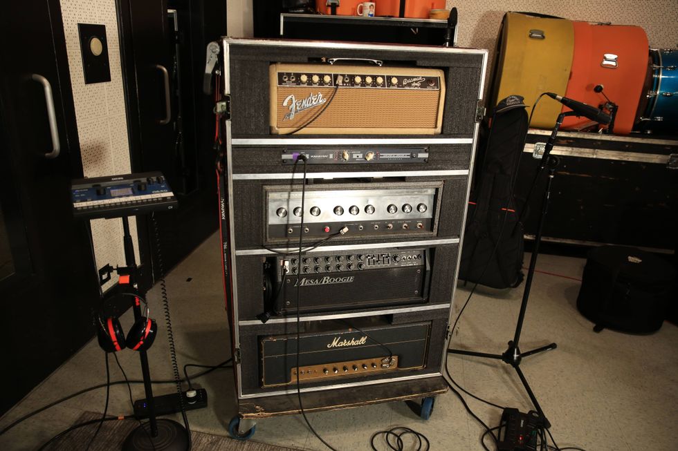 A stack of guitar amplifiers with various brands, next to mic and recording equipment.