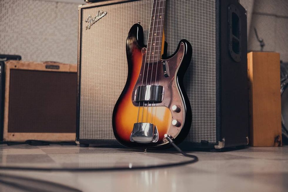 A vintage bass guitar leaning against an amplifier in a music studio.