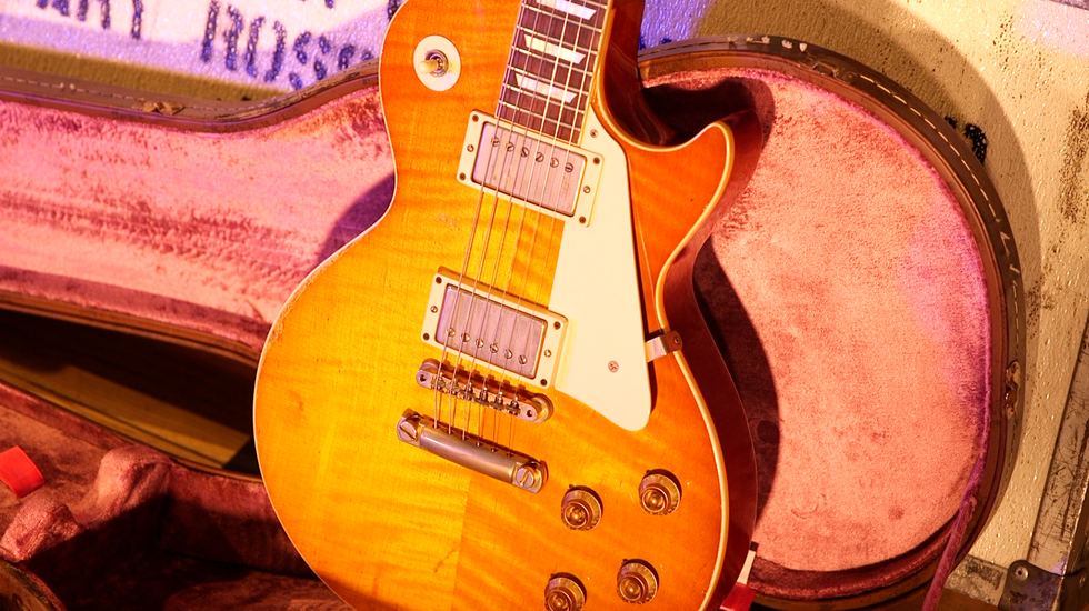 A vintage electric guitar in a pink-lined case, showcasing its polished wood and chrome hardware.