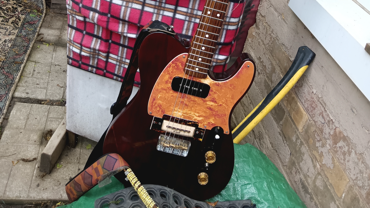 A vintage guitar leans against a burlap sack labeled "Canadian Hand Picked Beans."