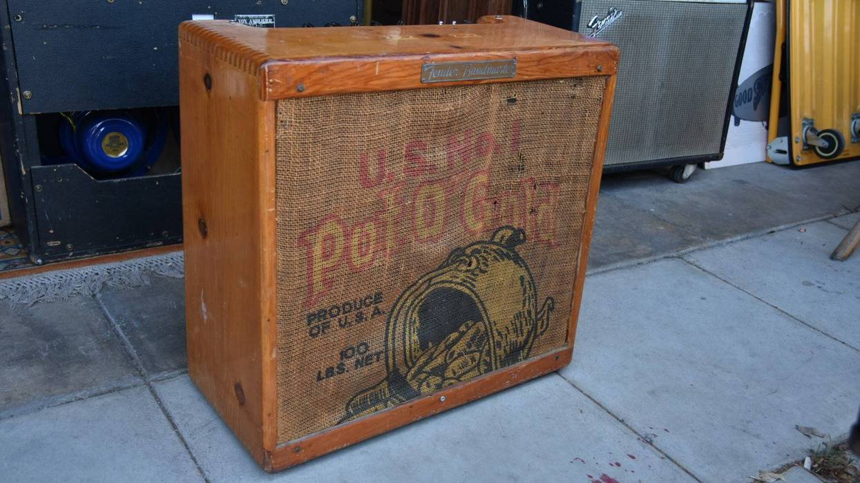A vintage wooden box with burlap featuring "U.S. Pot-O-Gold" branding, on concrete pavement.