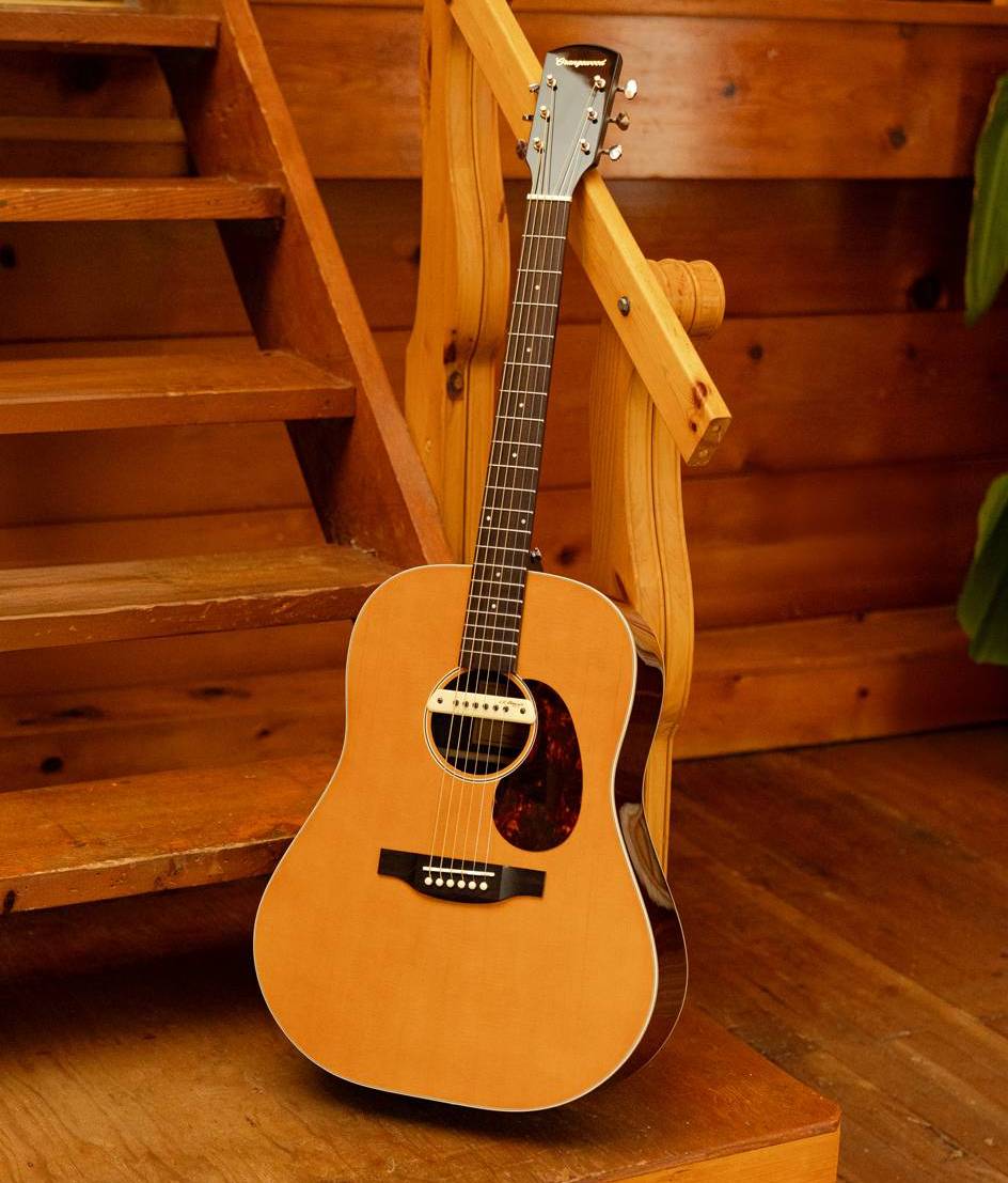Acoustic guitar resting on wooden stairs in a cozy, rustic setting.