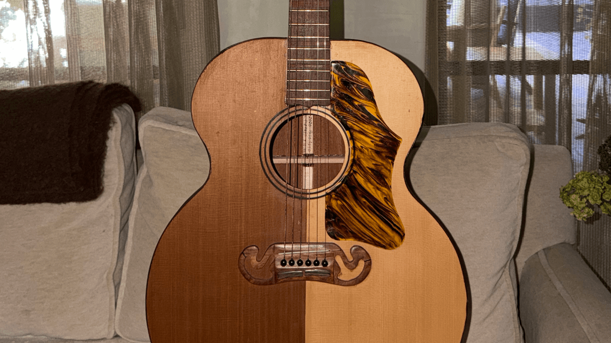 Acoustic guitar with a unique two-tone body and intricate pickguard on a couch.
