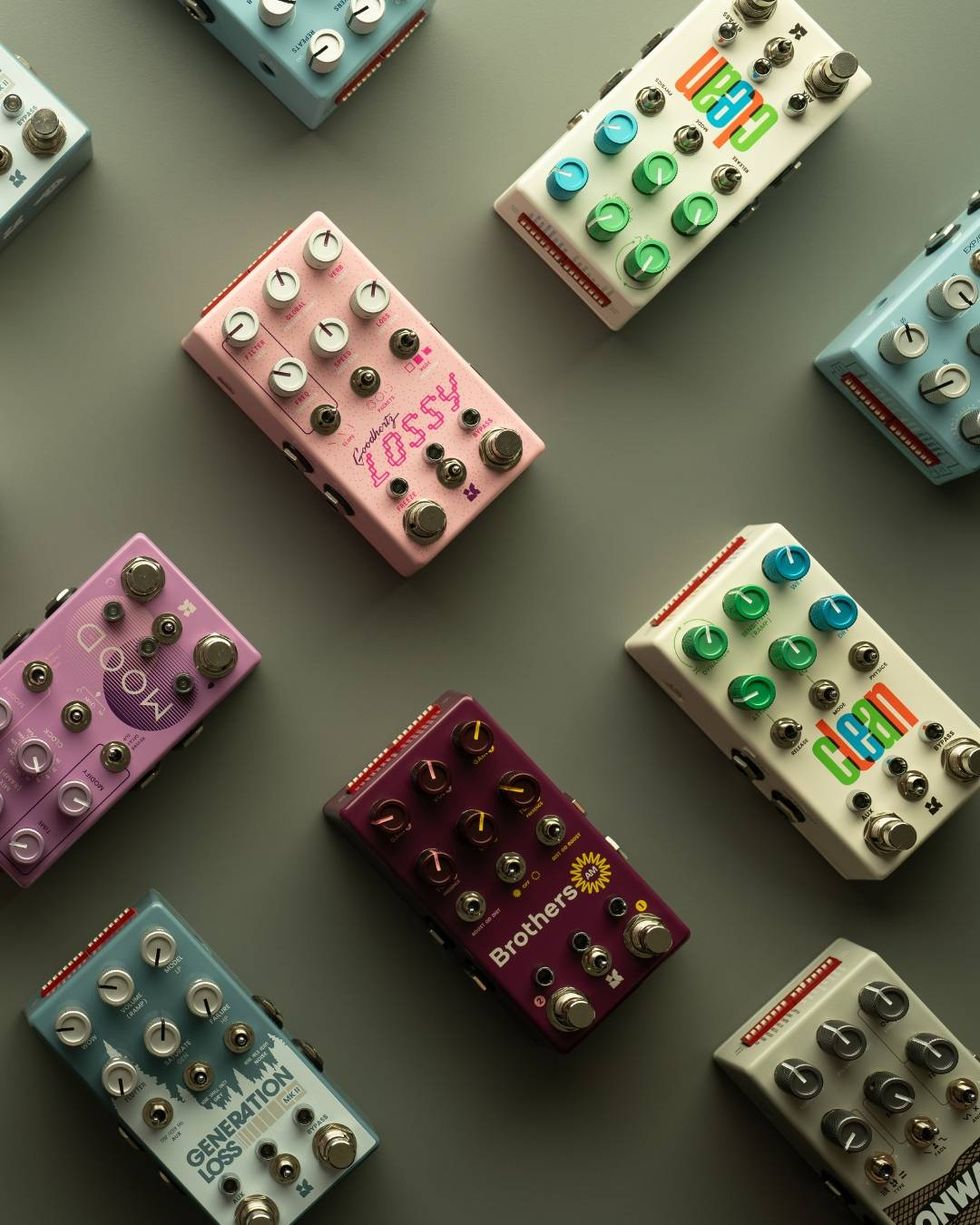Array of colorful guitar pedals arranged creatively on a gray background.