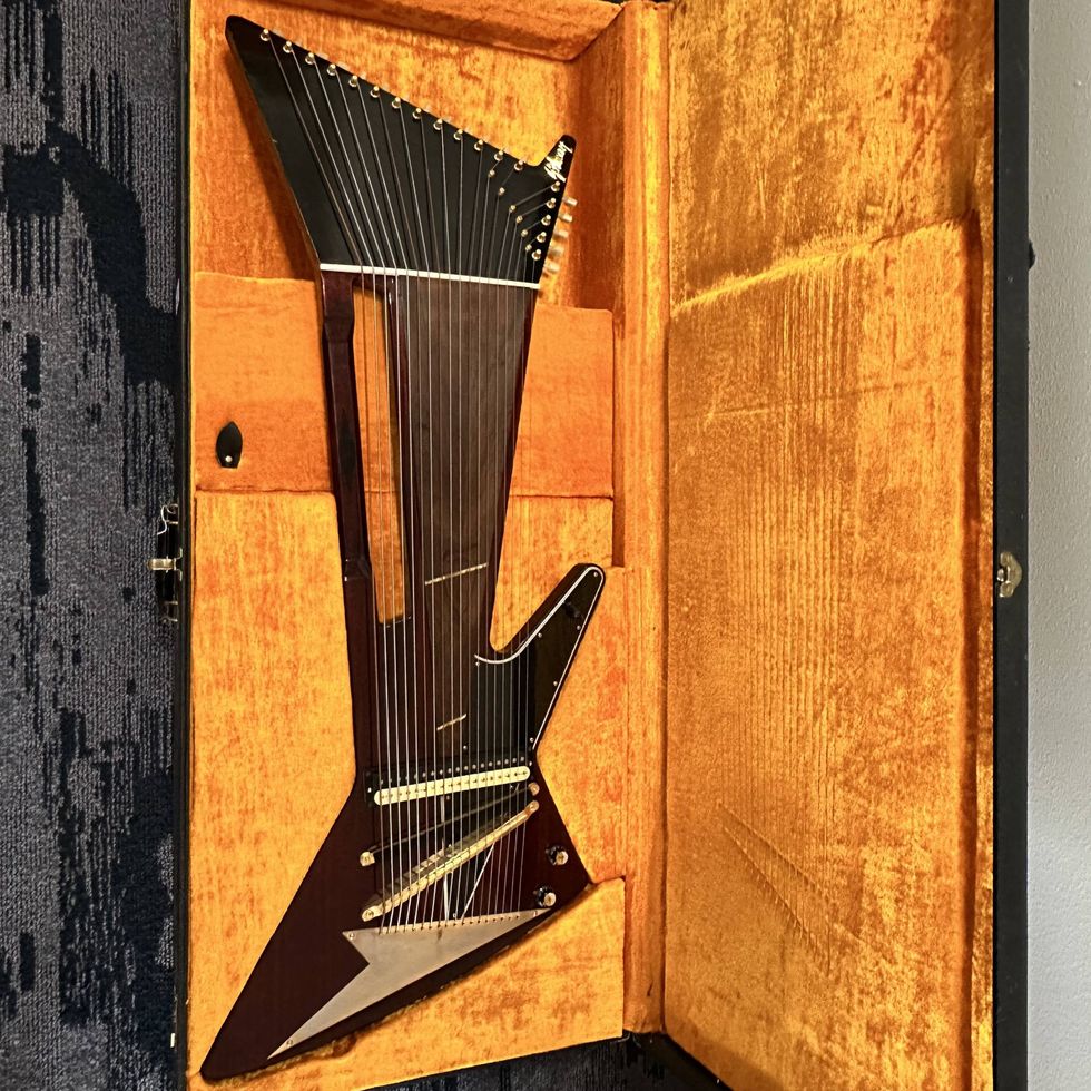 Black electric guitar with a lightning bolt design, resting in a velvet-lined case.