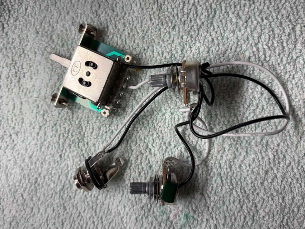 Circuit components including a switch, potentiometers, and wires on a textured surface.