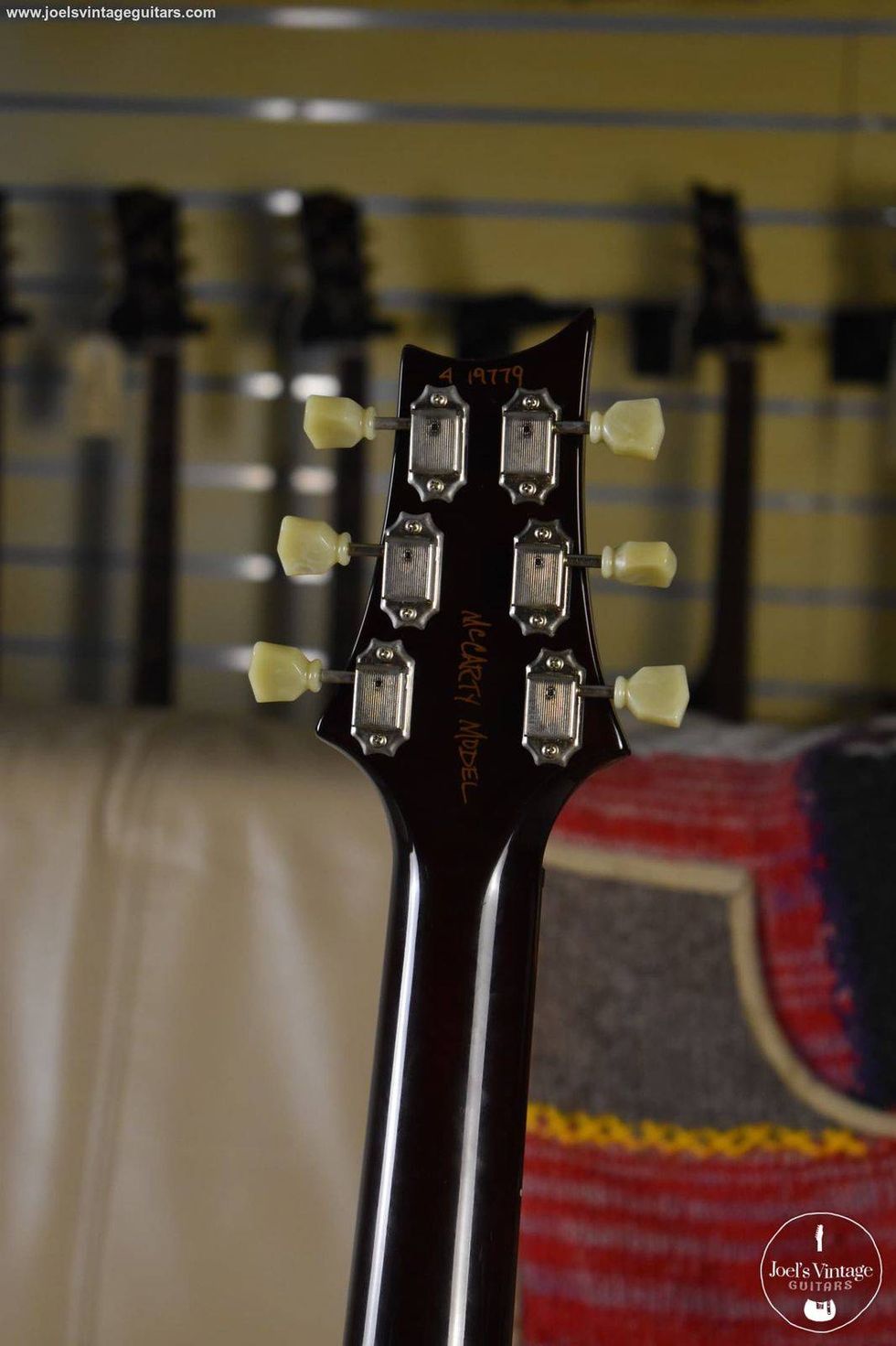 Close-up of a guitar headstock displaying tuning pegs and model name.
