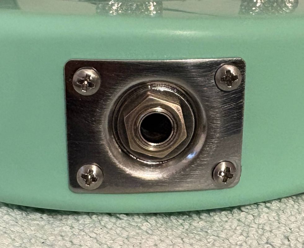 Close-up of a metal jack plate attached to a mint-green instrument body.