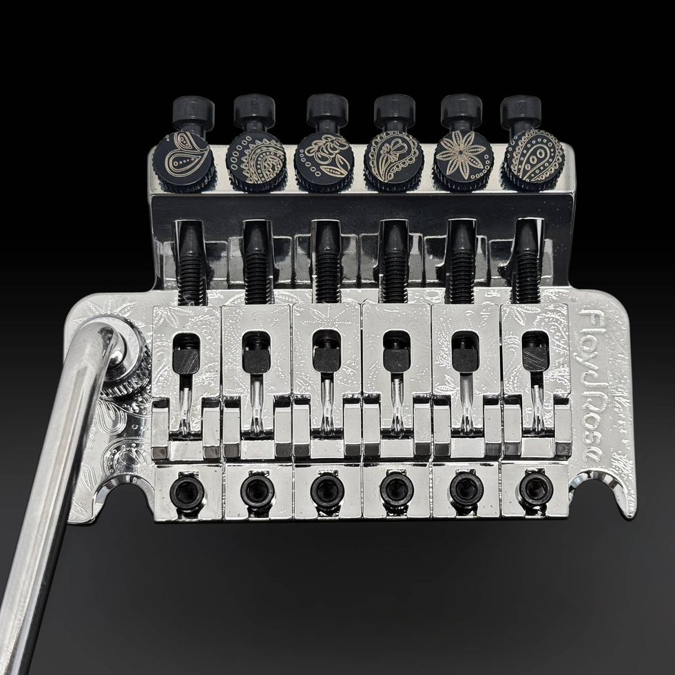 Close-up of a polished Floyd Rose guitar tremolo system with adjustment knobs.