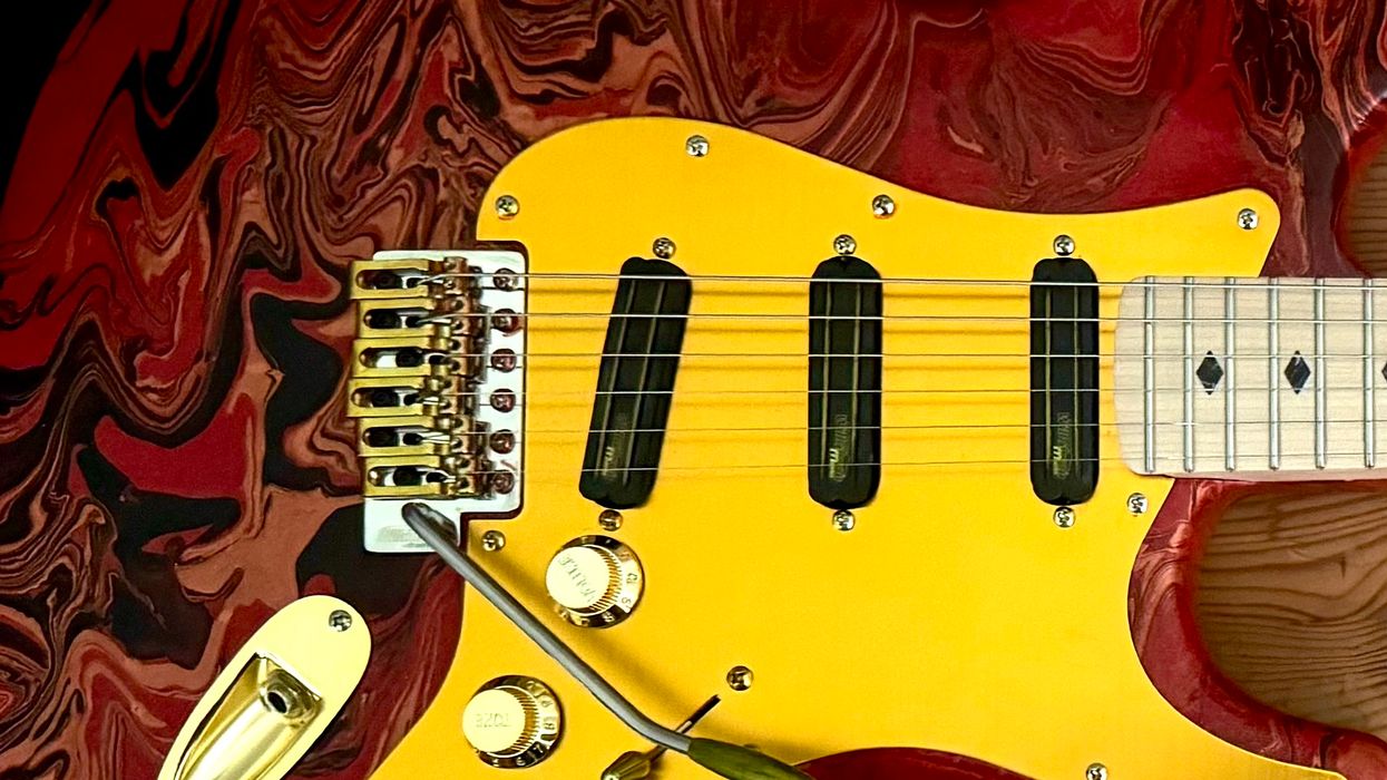 Close-up of a vibrant electric guitar with a yellow body and red marbled finish.