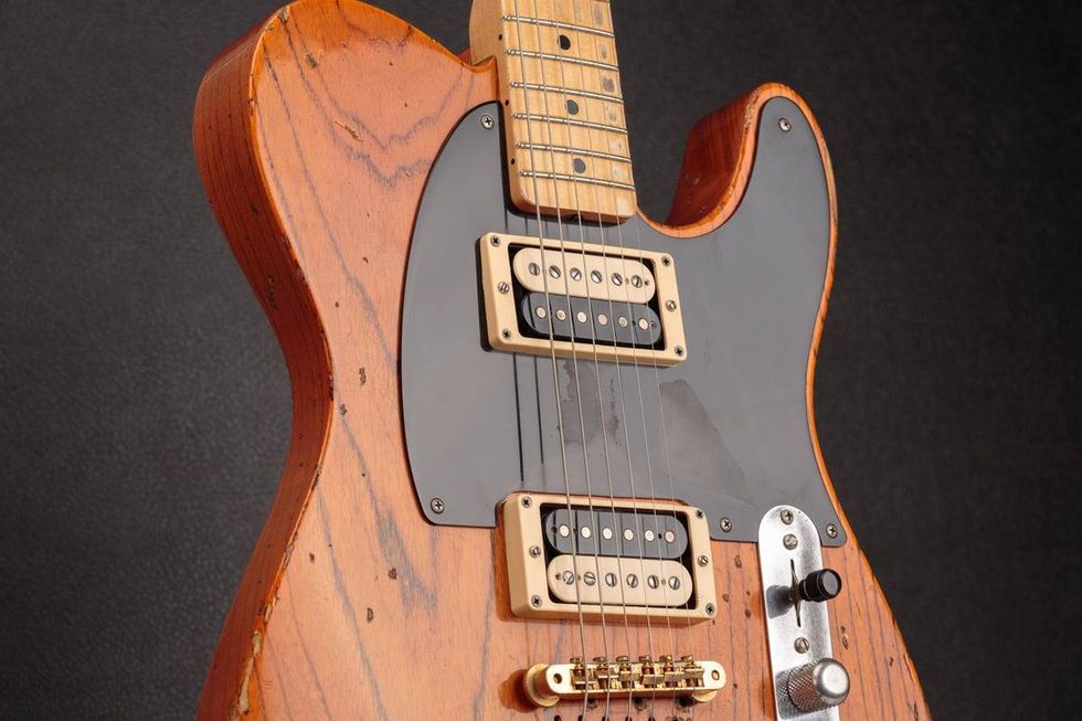 Close-up of a vintage electric guitar with a wood finish and black pickguard.