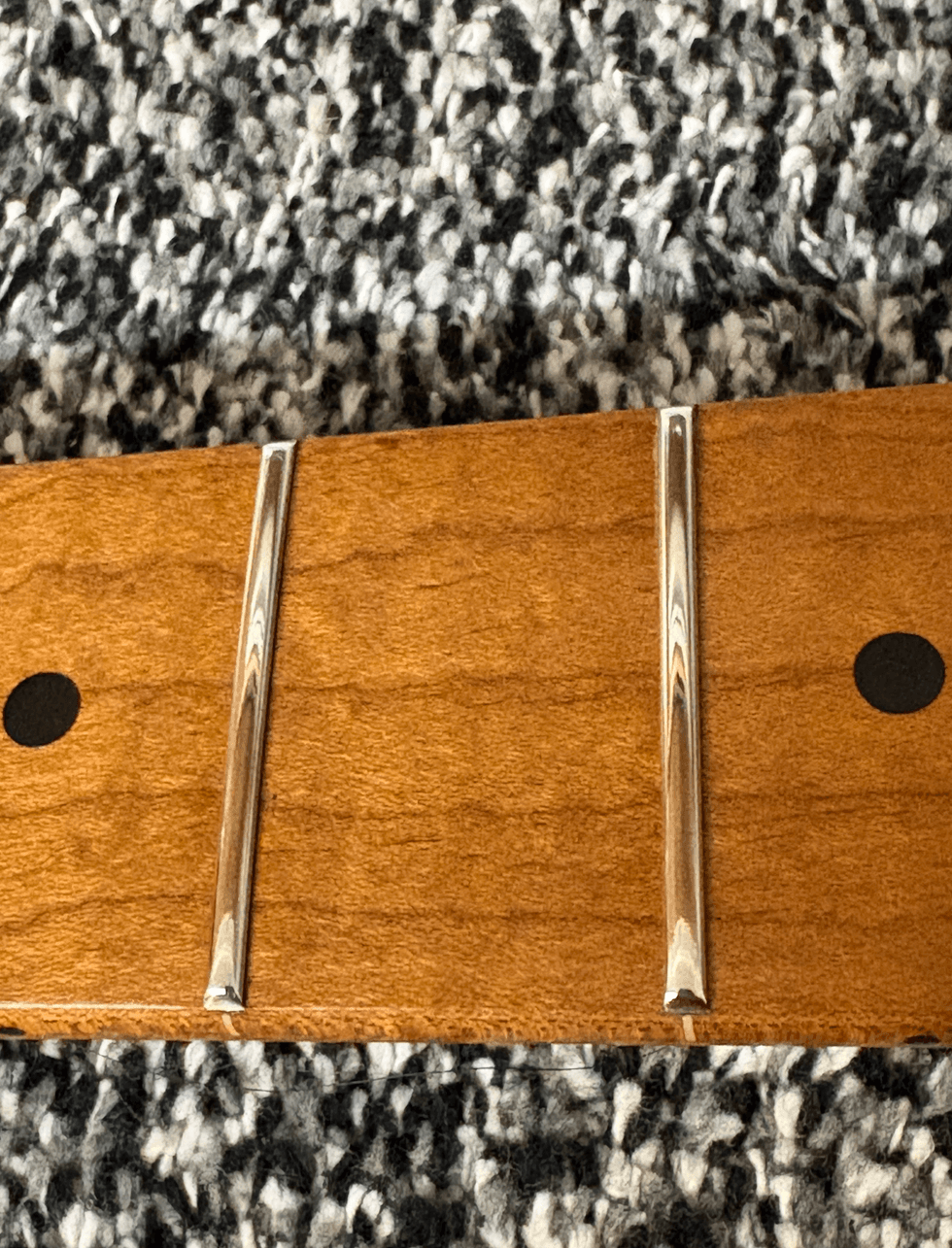 Close-up of a wood surface with two metallic inlays on a textured gray-black background.