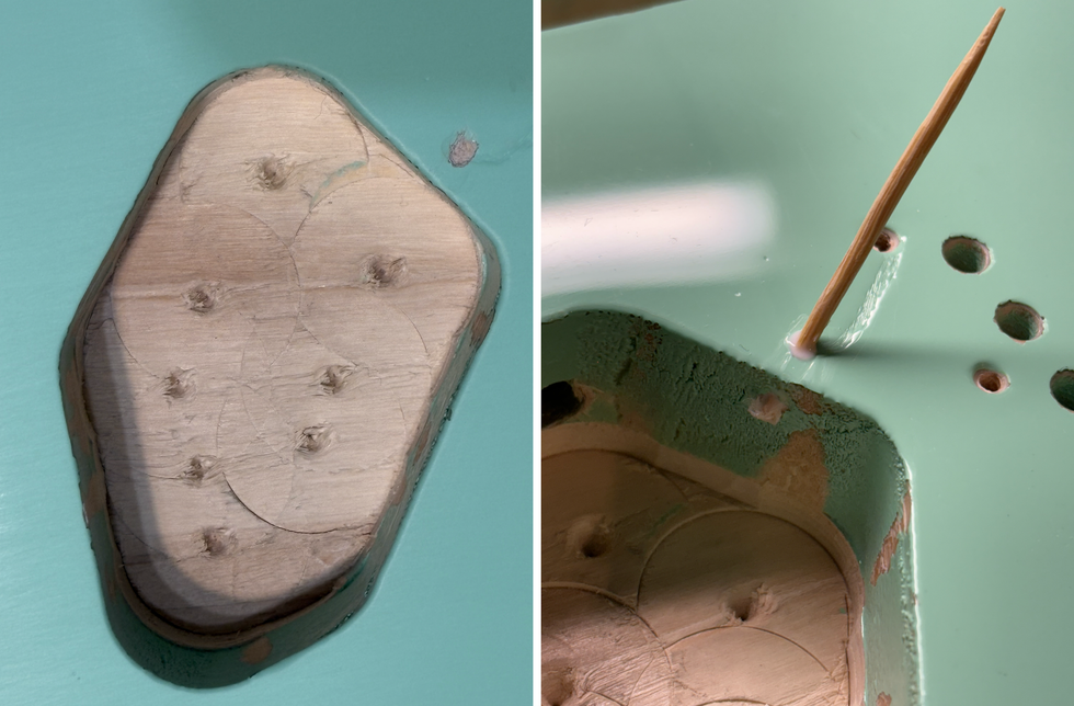 Close-up of a wooden base in a teal-painted surface with visible holes and a toothpick.