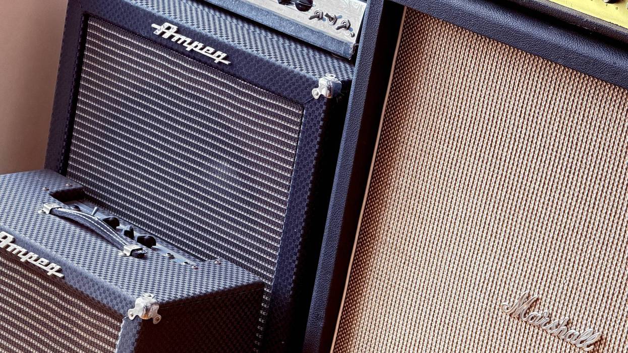Close-up of stacked guitar amplifiers, featuring Ampeg and Marshall brands with textured covers.