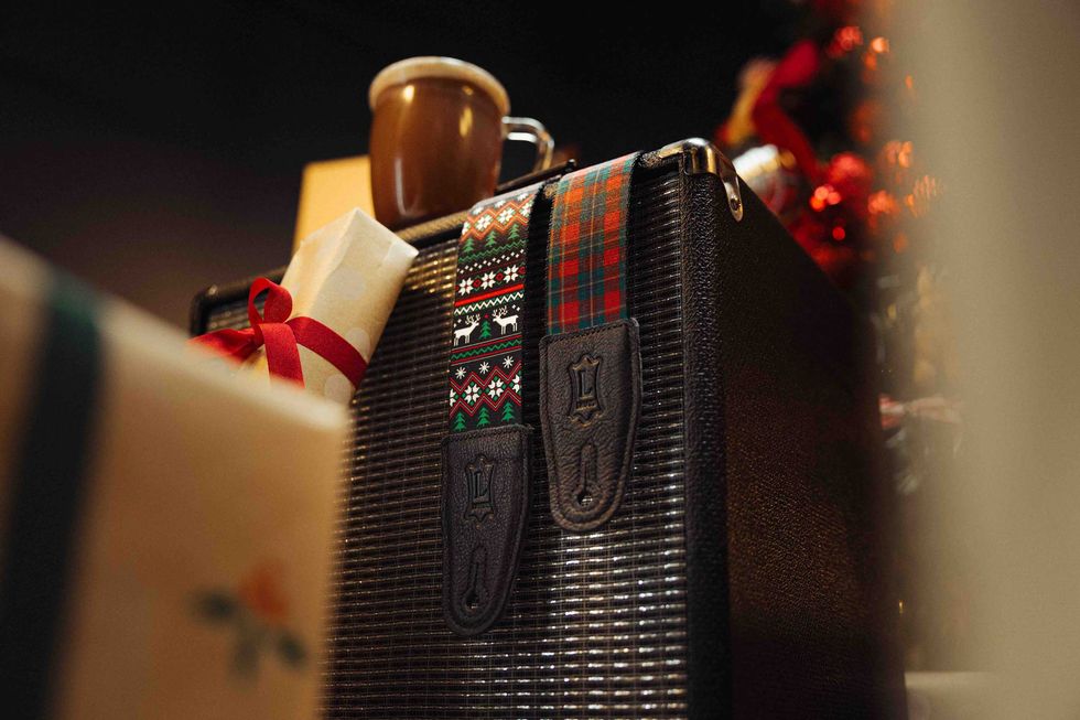 Coffee cup on a vintage suitcase surrounded by gifts and festive decorations.