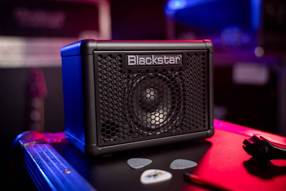 Compact Blackstar speaker on a surface with guitar picks and cables in a lit studio.
