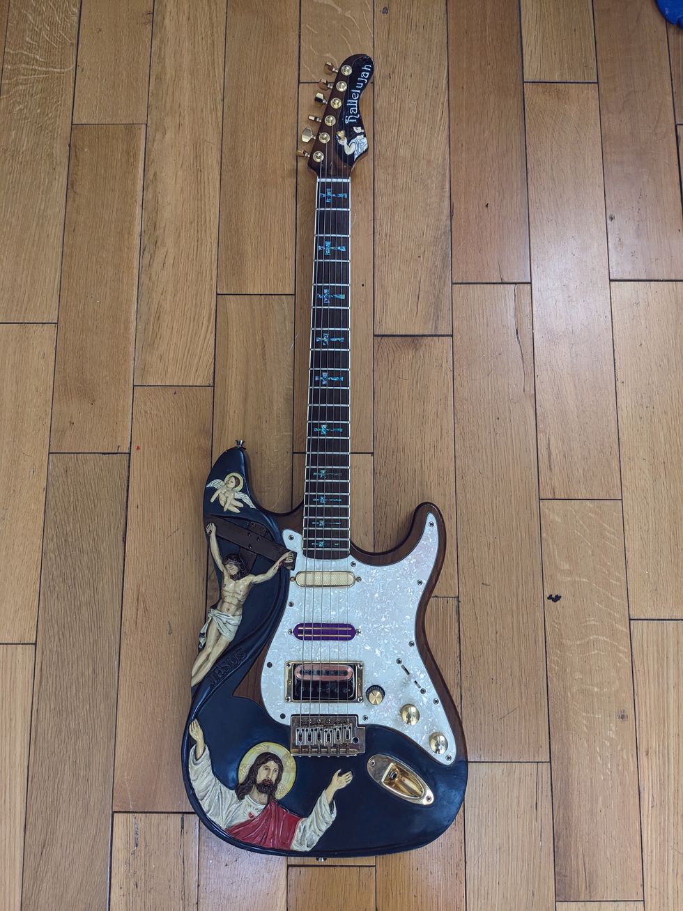 Decorative electric guitar featuring religious imagery on its body and gold hardware.