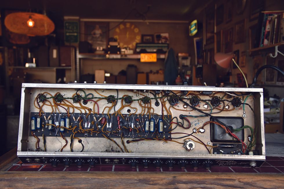 Detailed view of vintage amplifier internals with wires, resistors, and various components.