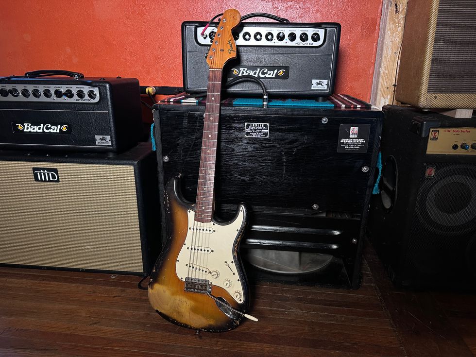 Electric guitar leaning against amplifiers in a music studio setting.