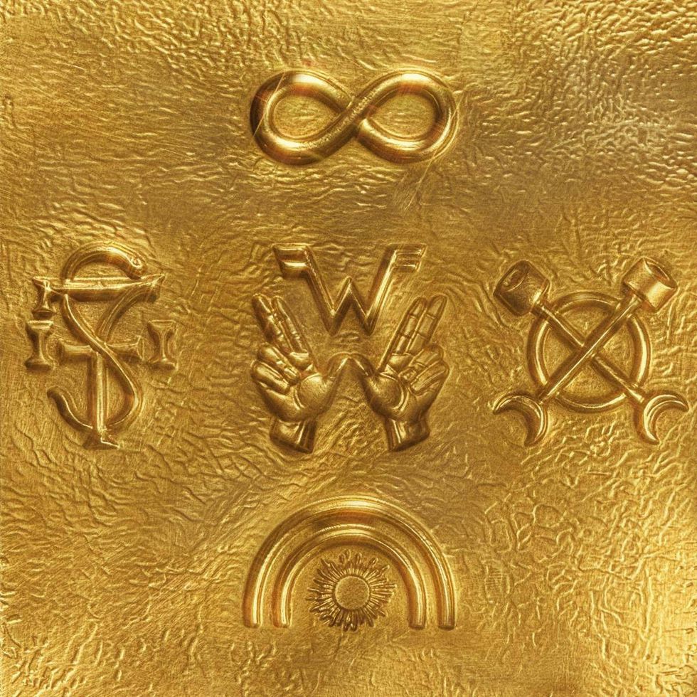 Embossed gold surface featuring various symbols: infinity, hands, sun, and tools.
