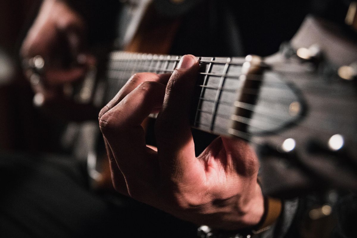 man playing guitar in close up photography