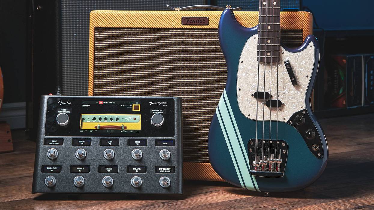 Fender amplifier and bass guitar next to a multi-effects pedal, on a wooden floor.