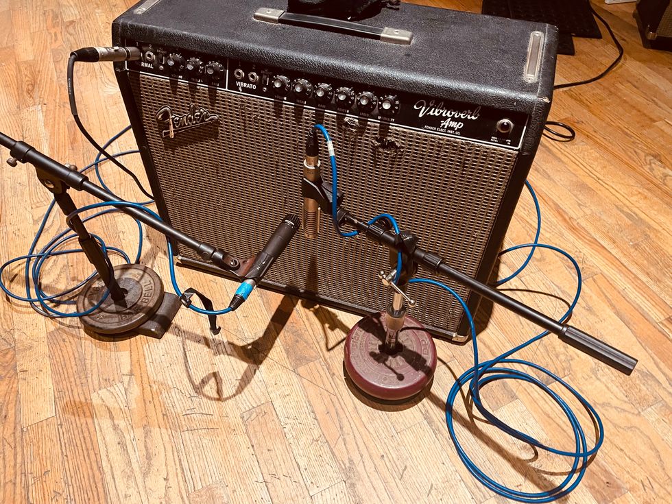 Fender amplifier with connected microphones and cables on a wooden floor.